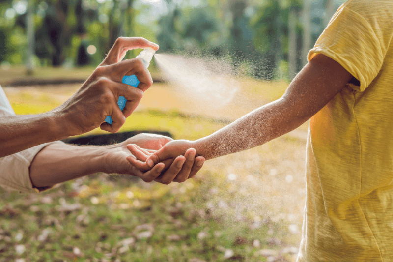 dad and son use mosquito spray