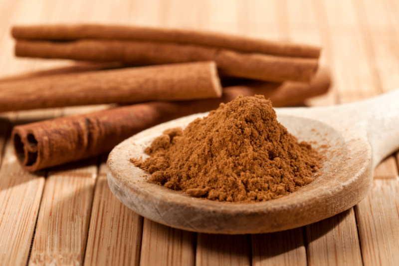 cinnamon, whole sticks behind a wooden spoon with a heap of powder - Natural Ways To Get Rid of Ants