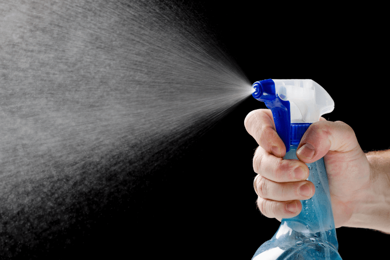 a man spraying a liquid sprayer on black background