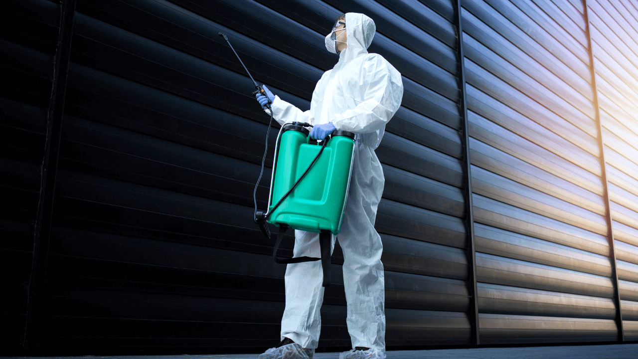 an exterminator in white protective suit doing pest control treatment in a commercial business