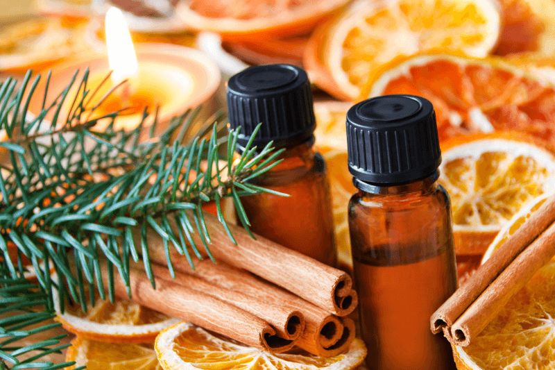 a group of bottles of essential oils with cinnamon sticks and orange slices