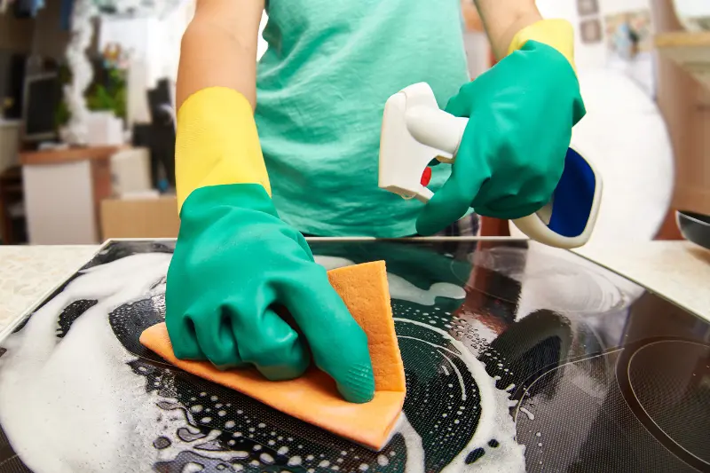 young woman cleaning a stove in her kitchen