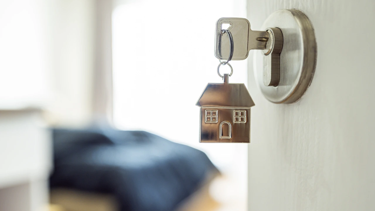 A close-up of a house key on a door handle, representing home rentals and pest control measures for Airbnb accommodations.  