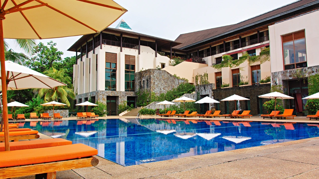 A large swimming pool with vibrant orange lounge chairs and umbrellas, ensuring a pleasant environment with pest control.  