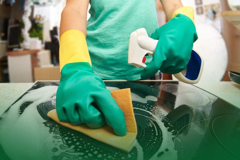 Hygiene Control Methods young woman cleaning a stove in her kitchen